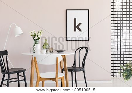 Poster In Black Frame On Pastel Pink Wall Of Sophisticated Dining Room Interior With Round Table