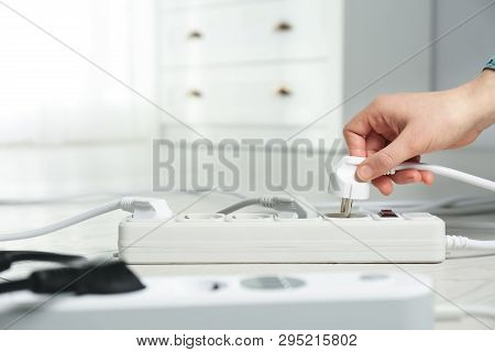Woman Inserting Power Plug Into Extension Cord On Floor Indoors, Closeup With Space For Text. Electr