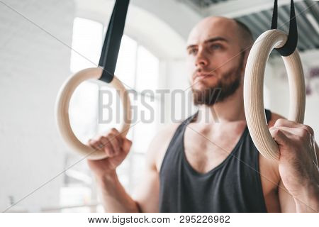 Close Up View On Male Gymnast Doing Workout On Gymnastics Rings In Cross Gym. Fit Athlete Exercises 