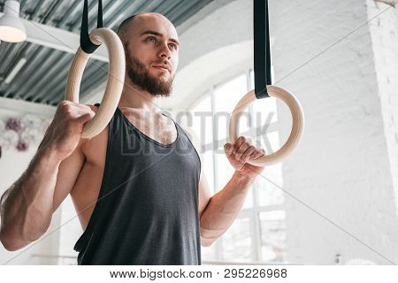 Profession Gymnast Holding Crosstraining Rings At Cross Hall. Muscular Man Holding Gymnastic Rings A