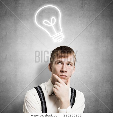 Redhead Student Thinking About Some Problem. Clever Boy On Background Of Grey Wall With Idea Lightbu