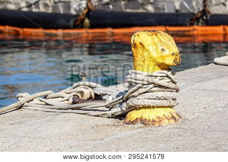 A Mooring Bollard Entwined With A Mooring Rope. Moored Ships At The Port Quay