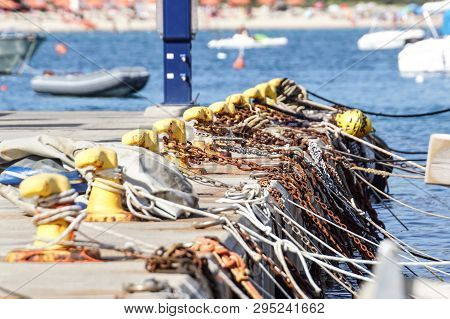 A Mooring Bollard Entwined With A Mooring Rope. Moored Ships At The Port Quay