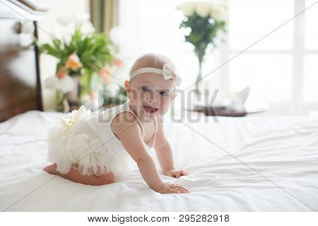 A Small Child Of 5 Months Is Having Fun Alone, Crawling On The Bed.baby Girl Crawling On Bed And Lau