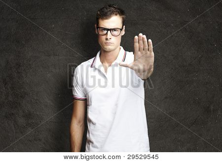 Portrait d'un beau jeune homme fait un symbole de butée contre un mur de grunge