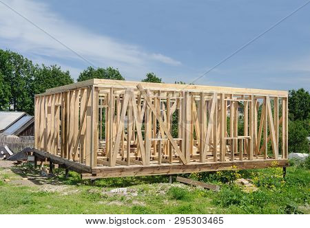 Frame Of A Wooden House Under Construction On A Pile Foundation, Racks And Partitions