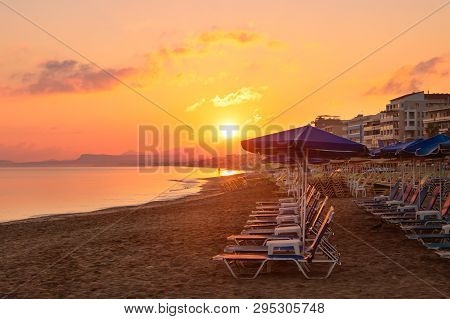 Morning On The Beach Near The Sea. Sun Chairs On Sandy Beach At Sunrise, Crete, Retimno. Beautifull 