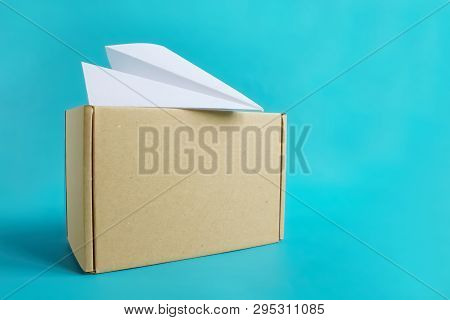 Air Cargo Concept. Paper Plane On Craft Box Isolated On Blue Background. Copy Space For Text