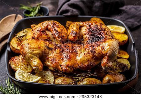 Fried Whole Tabaka Chicken With Potatoes In A Grill Pan, Dark Background.