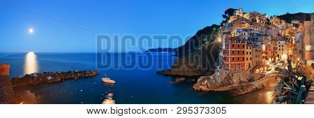 Riomaggiore waterfront view with buildings and moonset in Cinque Terre at night panorama, Italy.
