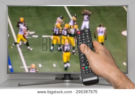 Rugby Match On Tv And Human Hand With Tv Remote Controller