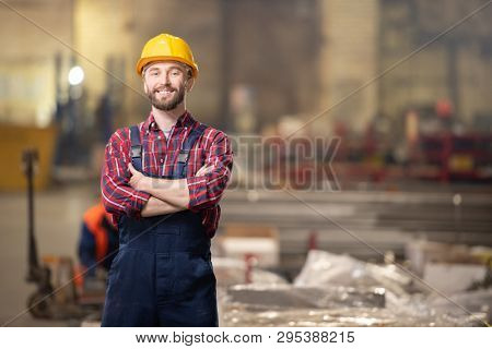 Young contemporary professional in machinebuilding industry standing inside workshop of large plant or factory
