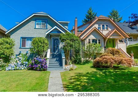 Snug Warm Family Houses Side By Side. Residential House With The Pathway Over Front Yard Lawn On Blu