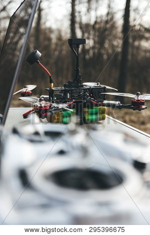 Fpv Drone Lies On The Table Near The Laptop And Control Panel. The Pilot Sets Up His Racing Drone Be