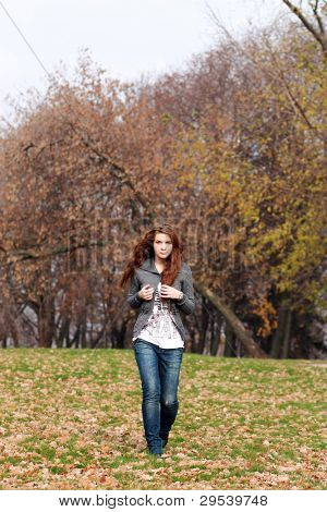 Young woman walking in a park. Autumn season