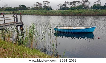 Blue Dinghy Tied Up  At A Jetty In The Calm Waters Near Marlo