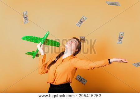 A Girl Throws Dollars To The Side And Holds A Green Plane In Her Hand, A Sign Of Freedom And Financi