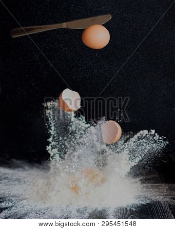 Eggs Are Broken By A Knife And Fall Into Flour On A Black Background.