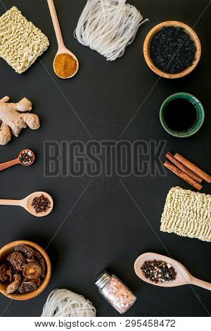 Chinese And Japanese Food Cooking With Ginger, Spices And Noodles Frame On Black Background Top View