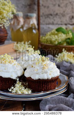 Chocolate Capcakes With Vanilla Cream Sprinkled With White Chocolate And Elderberry Flowers. Vintage