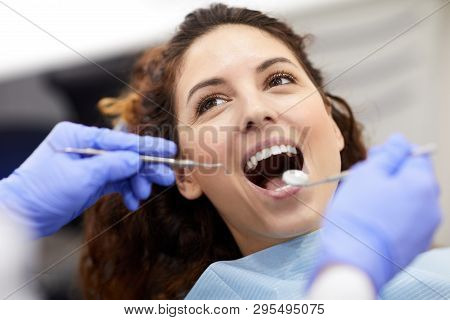 Head And Shoulders Portrait Of Beautiful Young Woman Lying In Dental Chair With Mouth Open During Co