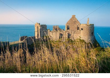 Dunluce Castle On A Sunny Day Looking Out On To The Irish Coast With Grass In The Foreground And The