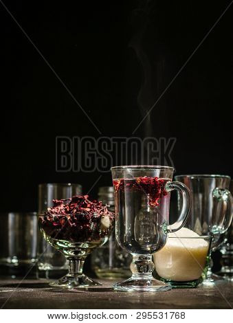 Transparent Glass Cup With Hot Red Tea From Hibiscus Or Hibiscus. Glassware And Dry Petals With Suga