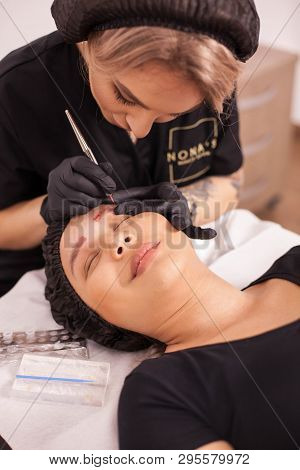 Female Cosmetician Removing Eyebrow Tattoo Using Modern Techonolgy In Her Salon