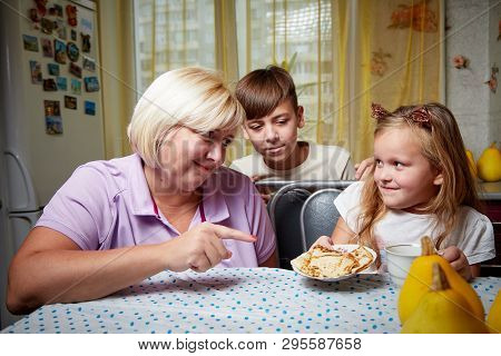 Kirov, Russia - November 04, 2018: Adalt Mother And Her Young Daughter And Son In A Kitchen With Pan