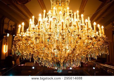 Chic Classic Chandelier With Lots Of Candles Burning Under The Ceiling