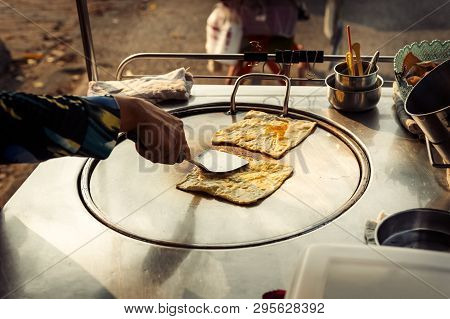 Hands Of Street Vendor Cooking Thai Style Sweet Roti Bread On Steel Roti Pan Or Big Flat Frying Pan.