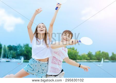 Young Smiling Woman In Light Clothes Is Holding White Racket And Ball In Her Hands. Cheerful Female 
