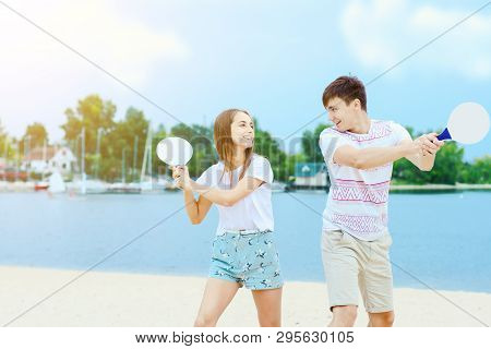 Young Smiling Woman In Light Clothes Is Holding White Racket And Ball In Her Hands. Cheerful Female 