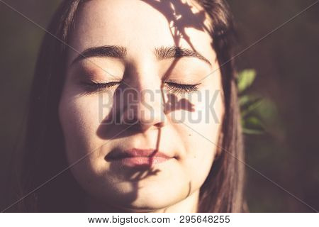 Young Woman Closeup Face Portrait In The Woods With Branch Of A Tree As A Gobo. Natural Beauty, Ecol