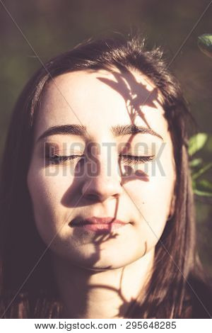 Young Woman Closeup Face Portrait In The Woods With Branch Of A Tree As A Gobo. Natural Beauty, Ecol