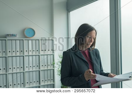 Concerned Businesswoman Reading Business Report Papers In Office, Financial Data Analysis And Strate