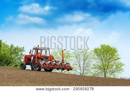 Unrecognizable Farmer Is Driving Tractor With Mounted Crop Seeder And Planting Corn Seed In Field