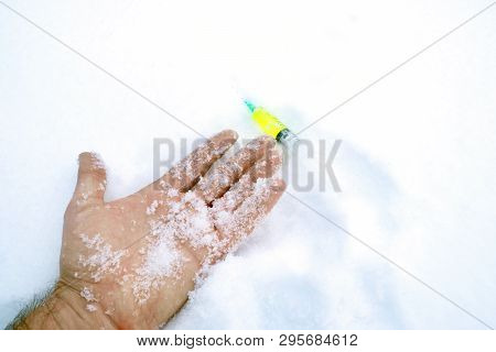 Syringe Lies Alongside Frostbitten Hand On Snow, The Danger In Winter Time From Drugs