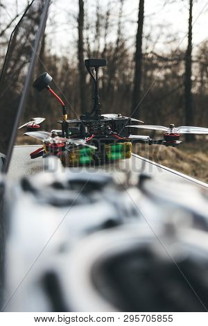 Fpv Drone Lies On The Table Near The Laptop And Control Panel. The Pilot Sets Up His Racing Drone Be