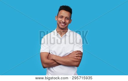 Charismatic African American Male In White Polo Shirt Keeping Arms Crossed And Smiling While Standin