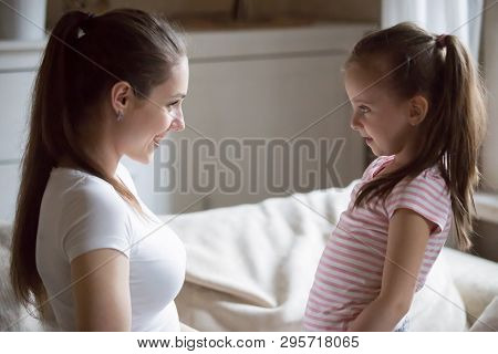 Happy Mother Looking At Smiling Daughter Holding Her Hands