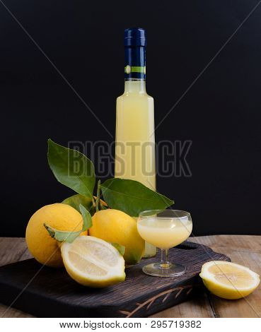 Lemoncello In A Bottle On A Black Background, Traditional Italian Liqueur From Lemons. Alcohol Yello