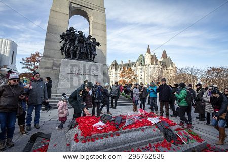 Ottawa, Canada - November 11, 2018: Soldier Putting Remembrance Poppy In Front Of A Crowd Gathering 