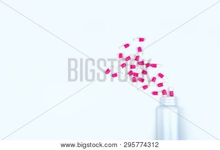 Pink-white Antibiotic Capsule Pills Spread Out Of White Plastic Drug Bottle. Antibiotic Drug Resista