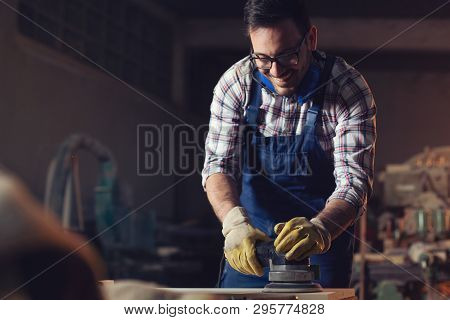 Young Carpenter Using Electric Sander For Wood