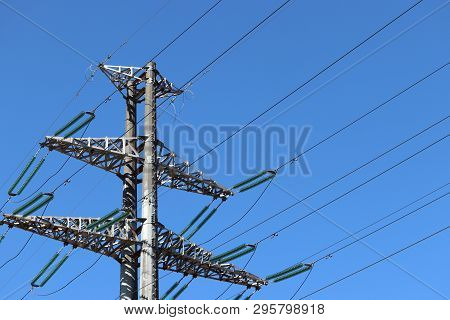 High Voltage Power Line Support With Electrical Wires On Background Of Clear Blue Sky. Electricity T