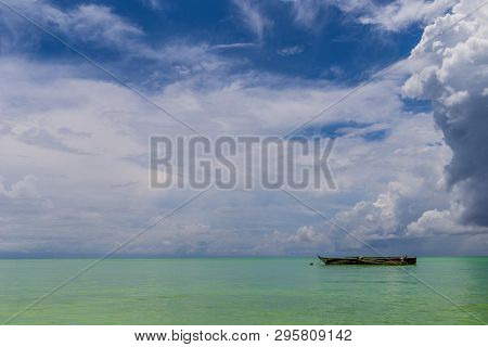One Old Homemade Wooden Fishing Bout In The Ocean Against The Horizon Under Blue Sky