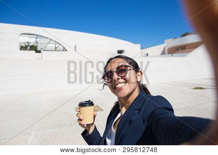 Joyful Office Employee Drinking Takeaway Coffee And Posing For Selfie. Self Portrait Of Smiling Youn
