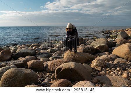 Young Archaeologist On A Boulder Beach Looking For Exotic Rocks On A Coastline Of A Baltic Sea