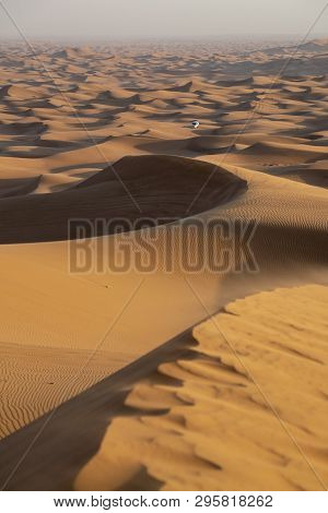 A Car Driving In The Far Distance Of The Arabian Desert.